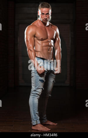 Portrait Of A Young Physically Fit Man In Jeans Showing His Well Trained Body - Muscular Athletic Bodybuilder Fitness Model Posing After Exercises Stock Photo