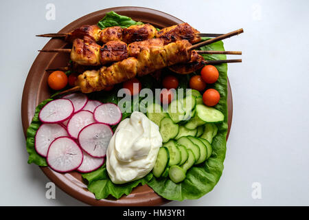 Chicken kebab with vegetables on a clay plate Stock Photo