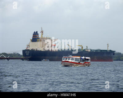 Small fishing boat with big container ship behind it Stock Photo