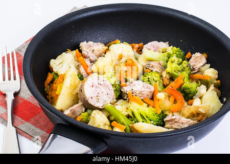 Vegetable stew with sausage grilled slices in a frying pan on a Stock Photo