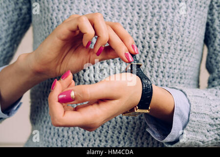 Women's hands with bright manicure fastens the strap on the watch. Stock Photo