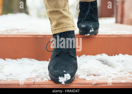 Women's legs in elegant winter boots down the snow-covered stairs, close-up Stock Photo