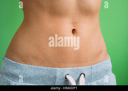 Close up of Belly slim girl in sweat pants on a green background, not isolated. Stock Photo