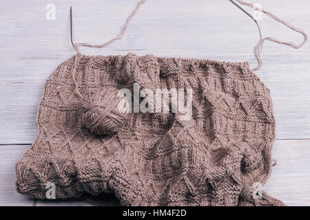 Knitted fabric with spokes lying on a wooden table Stock Photo