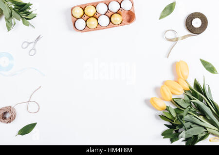 Painted eggs, tulips, rope, ribbon, scissors and place for text on a white background, top view Stock Photo