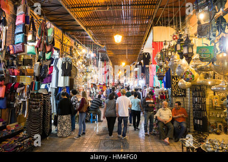 MARRAKECH, MOROCCO - APR 28, 2016: Tourists and locals walking through the souks in the old medina of Marrakech Stock Photo