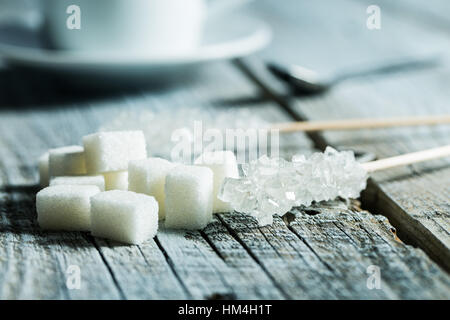 Crystallized sugar on wooden stick and sugar cubes on wooden table. Stock Photo