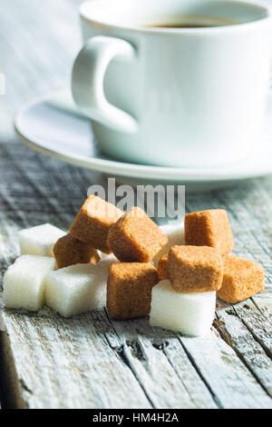 Brown and white sugar cubes on old wooden table. Stock Photo