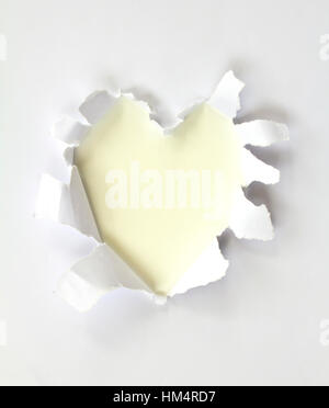 Sheet of paper with a Heart shape hole against bright white background isolated on white Stock Photo