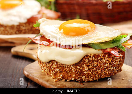 Sandwich with cheese bacon and fried egg on wooden background Stock Photo