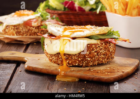 Sandwich with cheese bacon and fried egg on wooden background Stock Photo