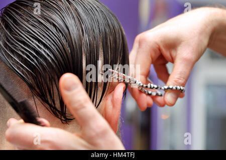 Hairdresser trimming hair with scissors Stock Photo