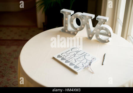 Wedding guestbook sat on a table with large word love at a wedding in Sussex, UK. Guests sign it with their heartfelt messages Stock Photo