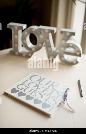 Wedding guestbook sat on a table with large word love at a wedding in Sussex, UK. Guests sign it with their heartfelt messages Stock Photo