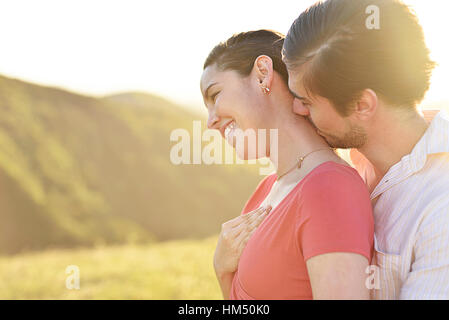 Man hugging and kissing in neck girl on sunny day Stock Photo