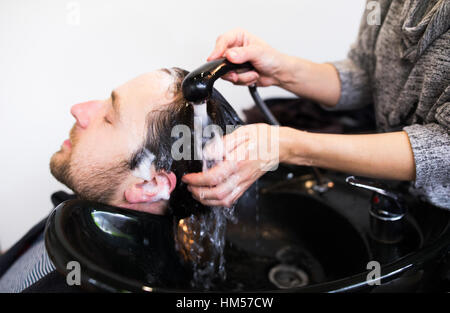 Professional hairdresser washing hair to her handsome client. Stock Photo