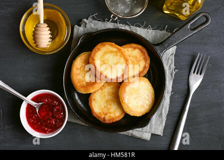 Cheesecakes, curd cheese pancakes in cast iron frying pan, top view Stock Photo