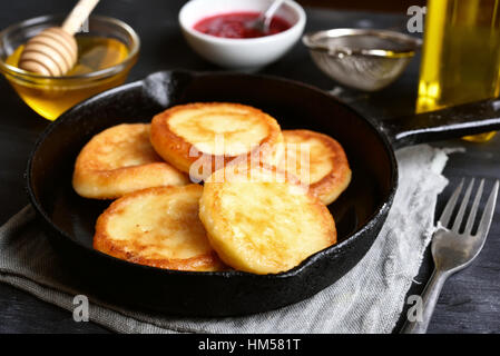 Fried curd cheese pancakes, cheesecakes in frying pan, close up view Stock Photo