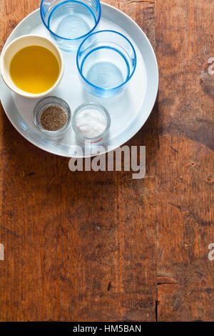 Serving dinner table. two empty blue glasses, olive oil, salt and pepper on the empty plates. on a wooden table Stock Photo