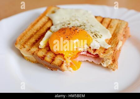 Ham and cheese toast with fried egg on top with missing bite. Stock Photo