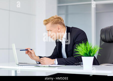 Businessman blonde working at a laptop  his desk in the office Stock Photo