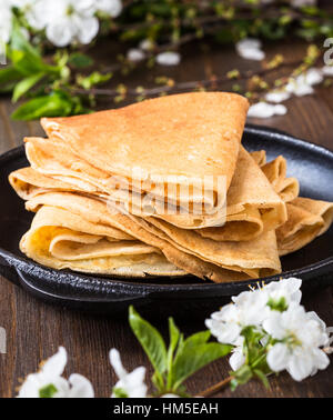 Homemade crepes  folded in triangles on frying pan on spring blossom background Stock Photo