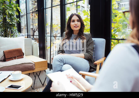 Woman holding book while sitting with colleague in cafe Stock Photo