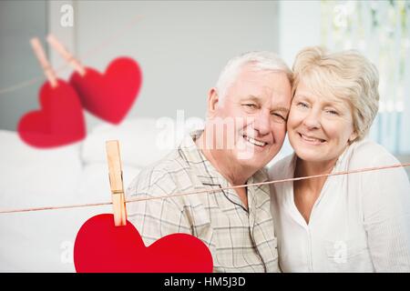 Composite image of hanging hearts and senior couple embracing each other Stock Photo