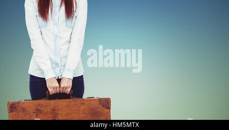 Mid section of woman holding heavy suitcase Stock Photo