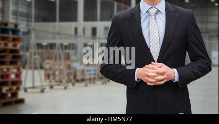 Businessman with hands clasped standing in warehouse Stock Photo