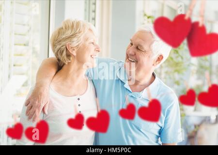 Composite image of red hanging hearts and senior couple embracing Stock Photo
