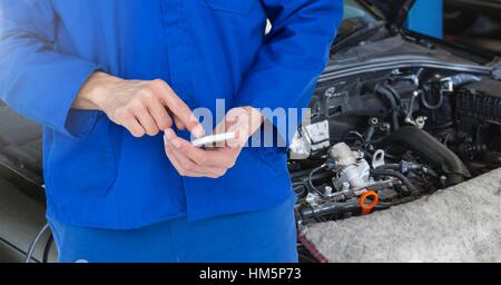 Mid section of car mechanic using mobile phone Stock Photo