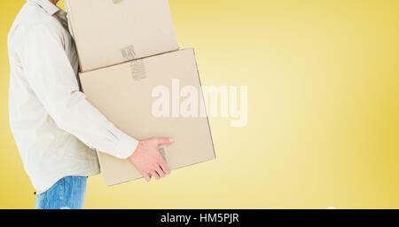 Delivery man carrying boxes against concrete wall Stock Photo