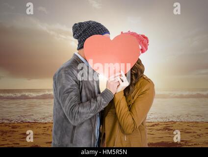 Couple kissing behind heart card Stock Photo - Alamy