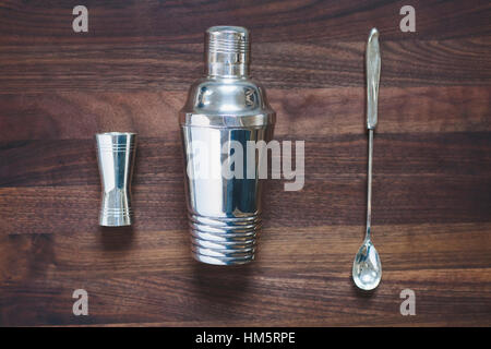 Overhead view of cocktail shaker with jigger and spoon on wooden table Stock Photo