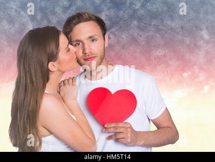 Woman kissing while man holding a red heart Stock Photo