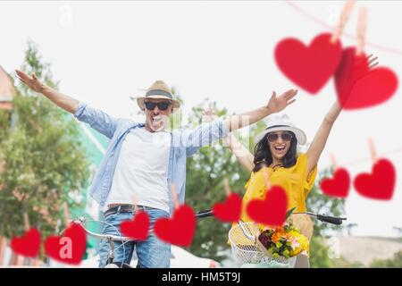 Composite image of couple enjoying together against hearts hanging on a line