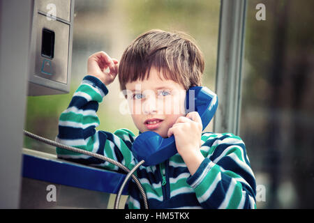 Cute little boy talking on the public phone Stock Photo