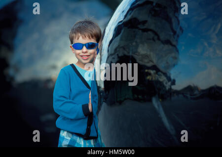 Cure little happy boy standing near Black ball sculpture in City of London Stock Photo