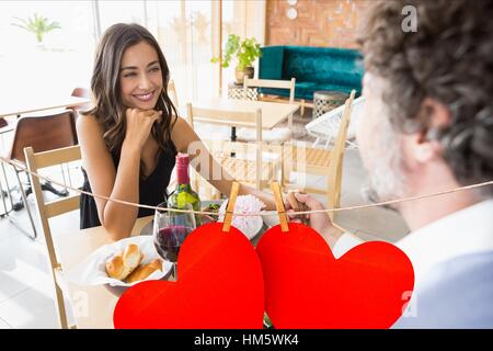 Couple having meal at restaurant with red hanging hearts Stock Photo