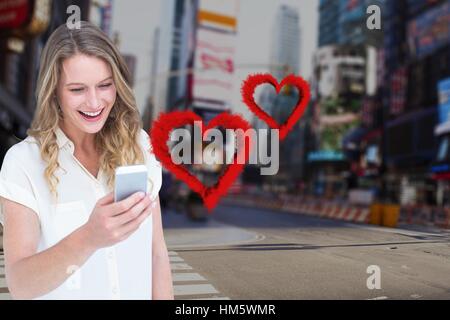 Smiling woman texting on mobile phone with digitally generated red hearts Stock Photo