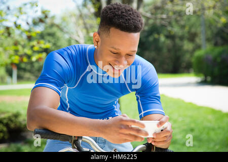 Man using smartphone to look at map while sitting on bike Stock Photo