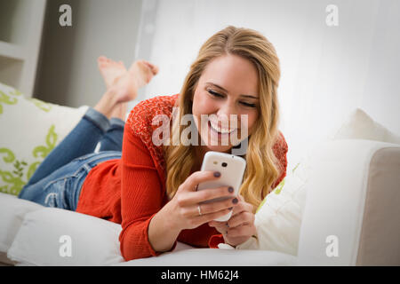 Young woman texting on sofa Stock Photo