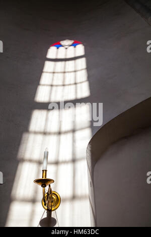 White church wall inside with rays of light going through stained glass window Stock Photo