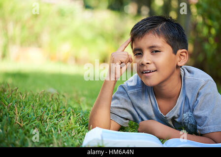 small boy learn from book on green grass in park Stock Photo
