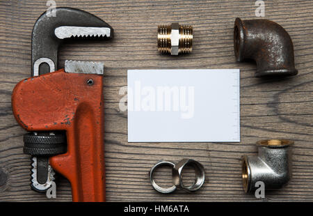 Set of pipes plumbing tools fittings and business card on the wooden background Stock Photo