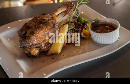 baked pork leg on white horizontal plate with bbq sause Stock Photo