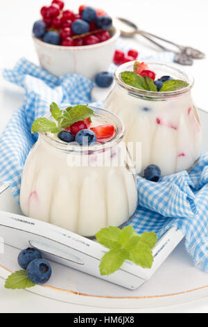 Fresh yogurt with berries and wafer rolls. On white table. Stock Photo
