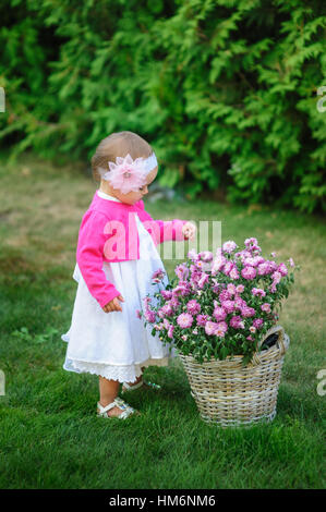 little girl stands near a basket of flowers Stock Photo