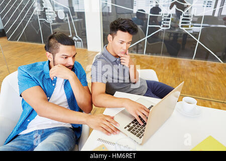 Programmers working in team with laptop computer in start-up company Stock Photo